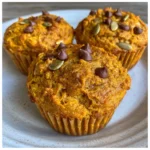 Fluffy pumpkin protein muffins stacked on a cooling rack.